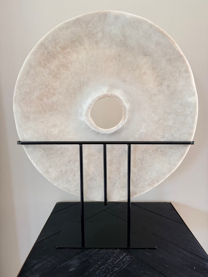 Achterzijde van ronde zandstenen decoratie op zwarte metalen standaard