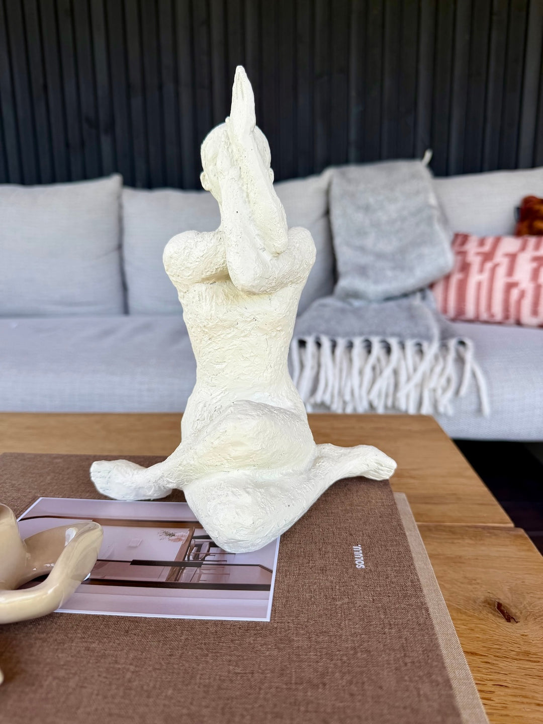 Yoga beeld en beige strik kandelaar gestyled op opbergboeken Calm Living en Slow Spaces