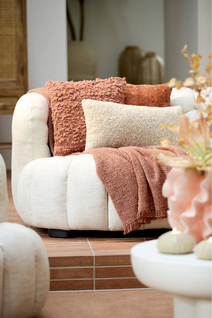 Beige sierkussen op bank gecombineerd met warme woonaccessoires