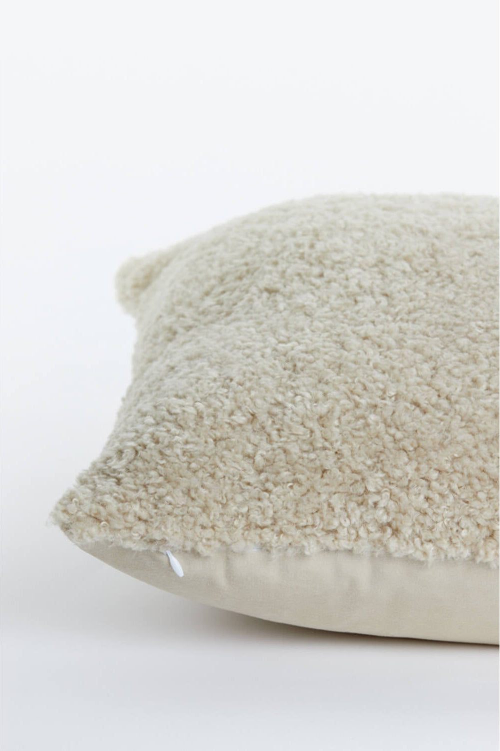 Detailfoto beige sierkussen met zachte teddy structuur