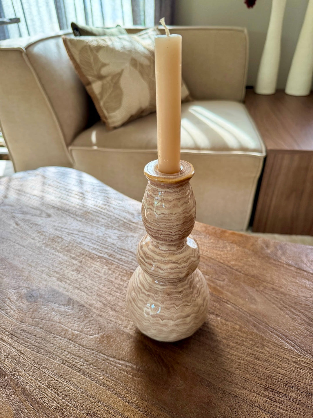 Zandkleurige kandelaar met dinerkaars op een houten tafel