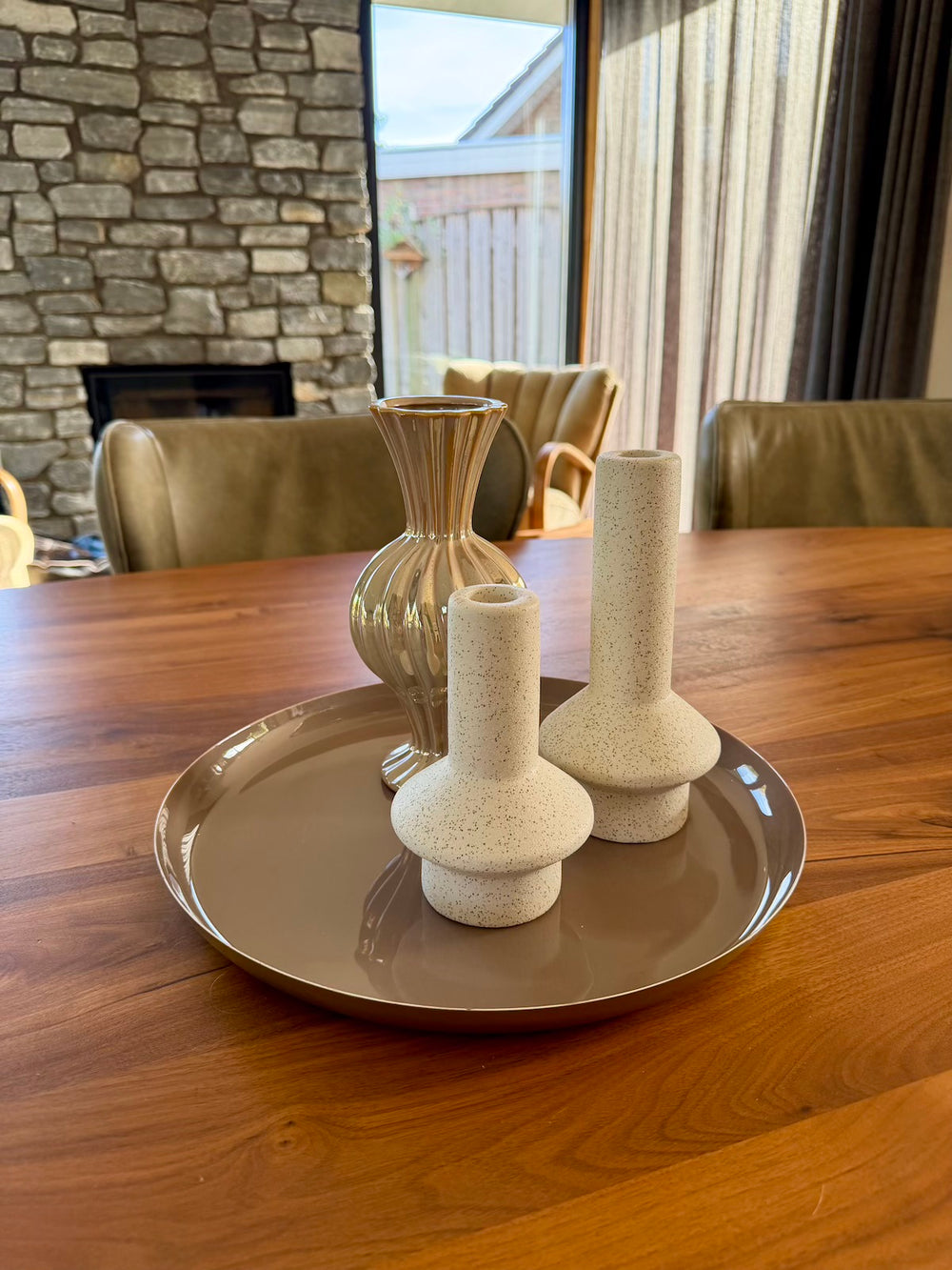 Taupe decoratieplateau gestyled met een vaas en zandkleurige kandelaars